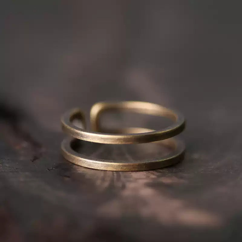 Double band copper ring on a dark wood surface