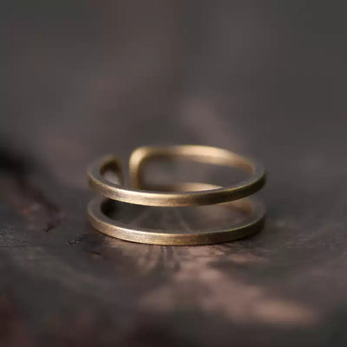 Double band copper ring on a dark wood surface