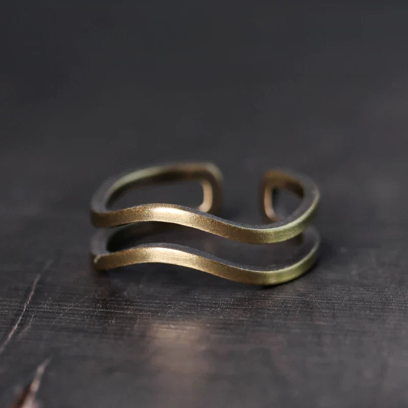 Double wave copper ring on a dark wood surface