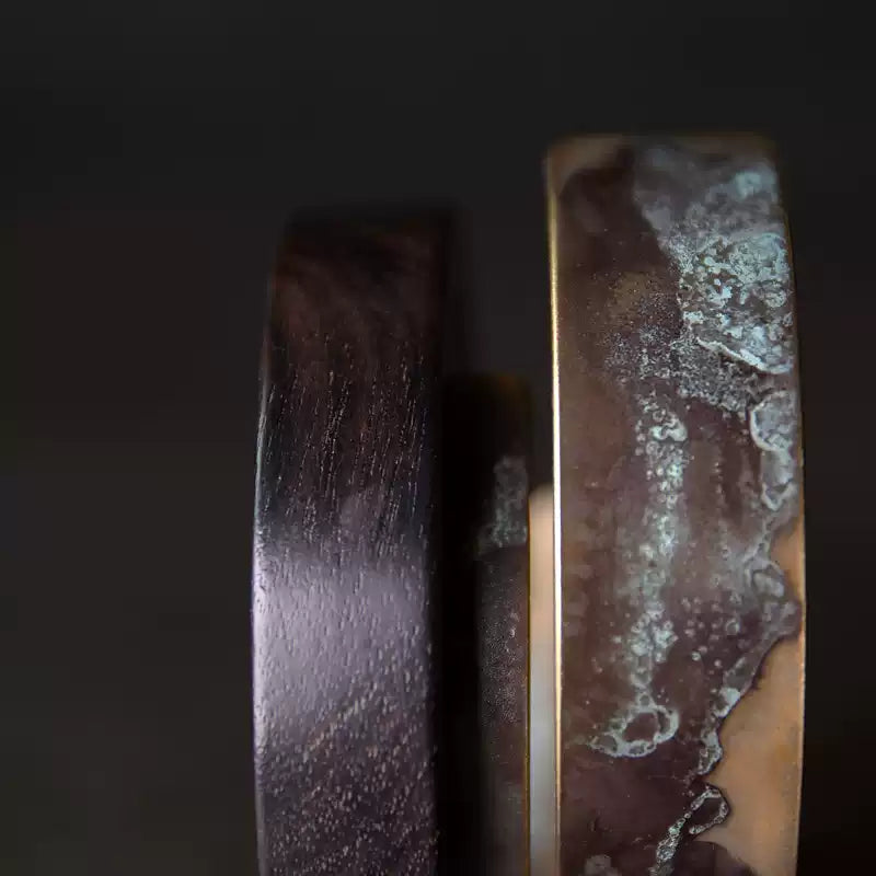 Close-up of verdigris patina texture on the copper band beside the ebony wood edge
