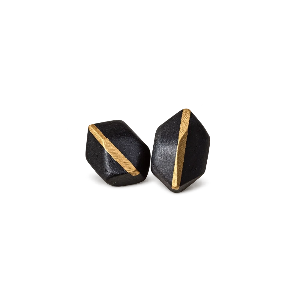 Pair of faceted ebony wood stud earrings with a diagonal copper inlay, white background