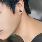 Man wearing a single ebony wood stud earring with copper inlay