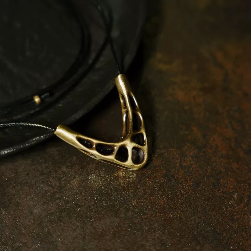 Close-up of the organic openwork copper pendant on black cord