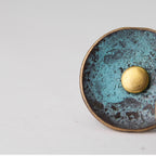 Macro close-up of verdigris patina and domed center on a round copper stud