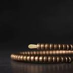Low-angle close-up of the copper coil bracelet showing ribbed segments and flat end