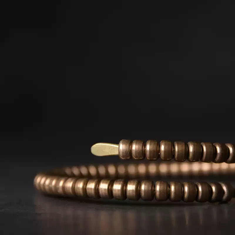 Low-angle close-up of the copper coil bracelet showing ribbed segments and flat end