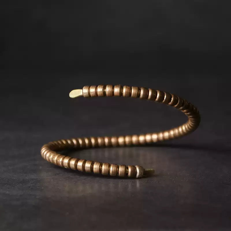 Side view of the spiral copper wrap bracelet on a dark background