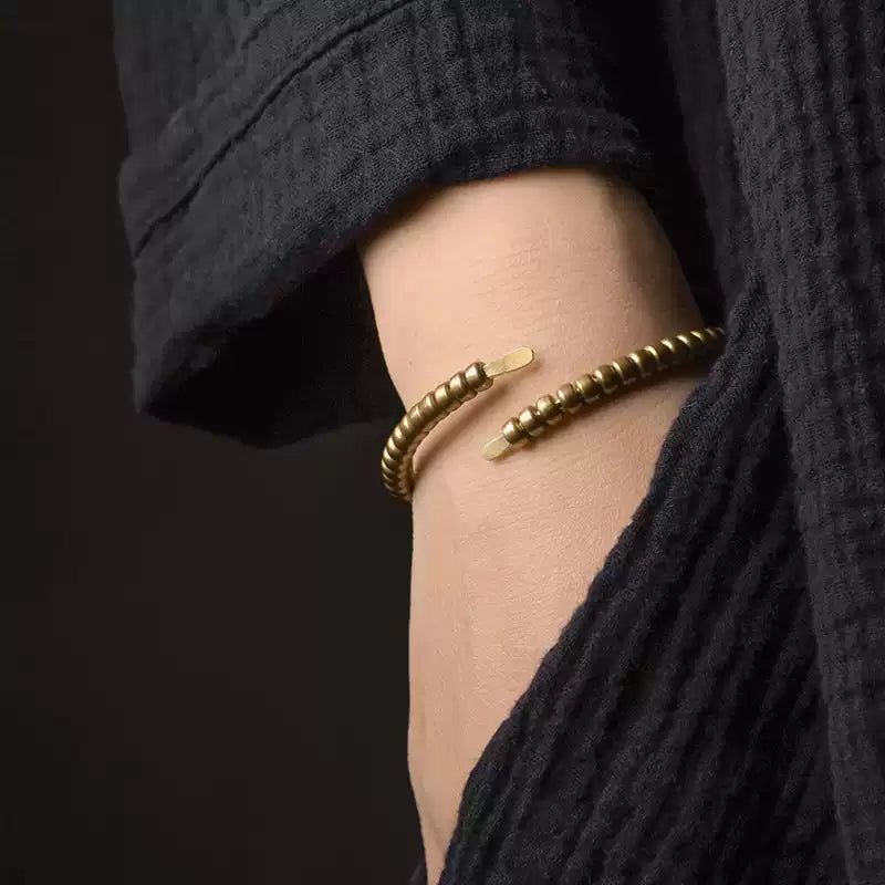 Copper coil wrap bracelet on the wrist with hand in a black linen pocket
