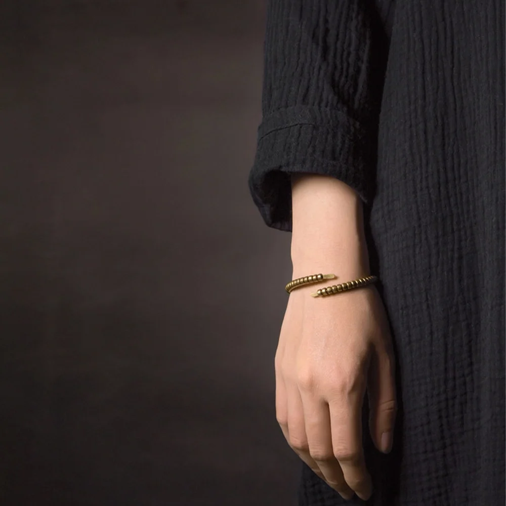 Model wearing the segmented copper wrap bracelet with a black linen dress