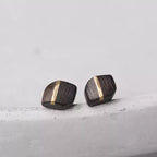 Square ebony wood studs with a copper stripe on a concrete surface