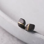 Angled view of square ebony stud earrings with copper inlay
