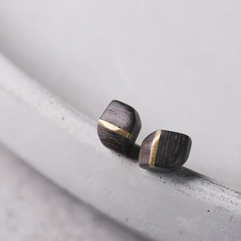 Angled view of square ebony stud earrings with copper inlay
