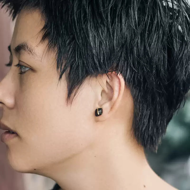 Side profile of a person wearing a small square ebony wood stud earring