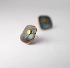 Angled view of square verdigris copper stud earrings