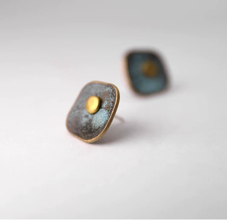 Angled view of square verdigris copper stud earrings