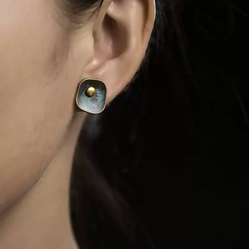 Woman wearing a square verdigris copper stud earring