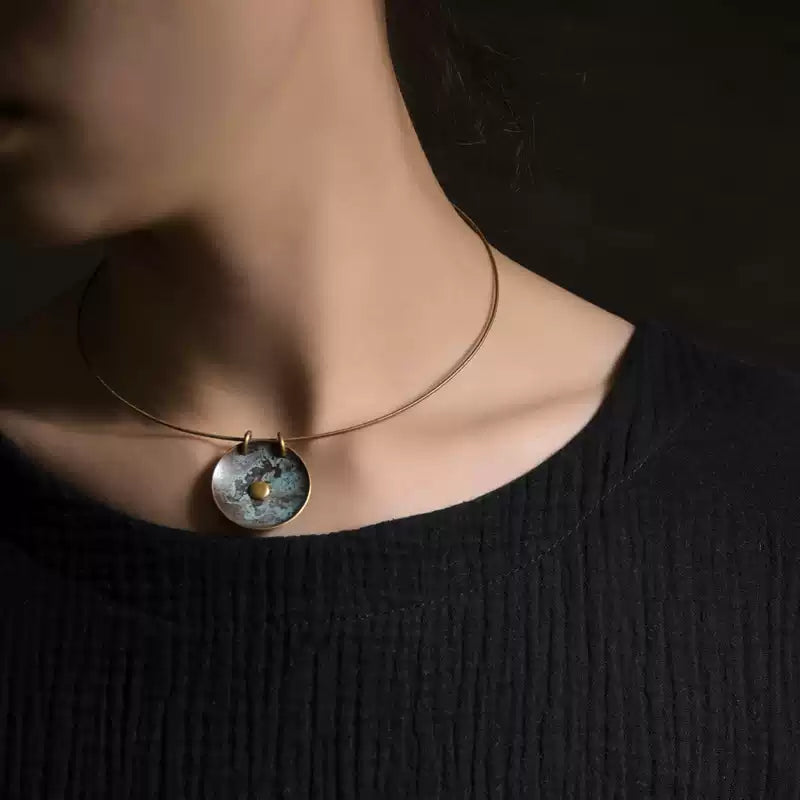 Woman wearing the verdigris copper disc pendant collar necklace with a black top