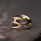 Wavy cutout copper ring on dark wood