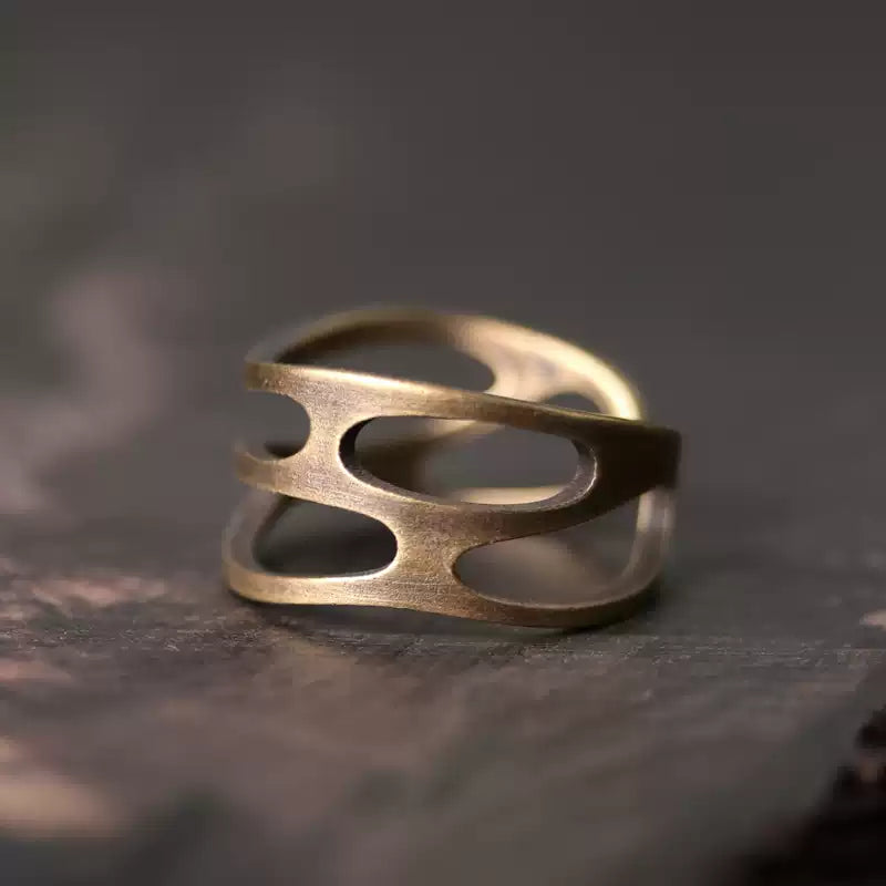 Wavy cutout copper ring on dark wood