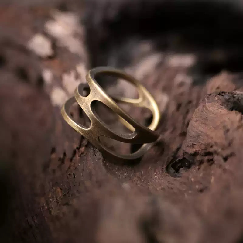 Wavy copper ring resting on rough dark tree bark