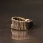 Close-up of fine coiled copper wire wrapping on the wide ring band